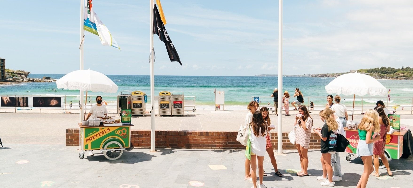 Guests gathering around colourful Gathering Events food carts beside the beach